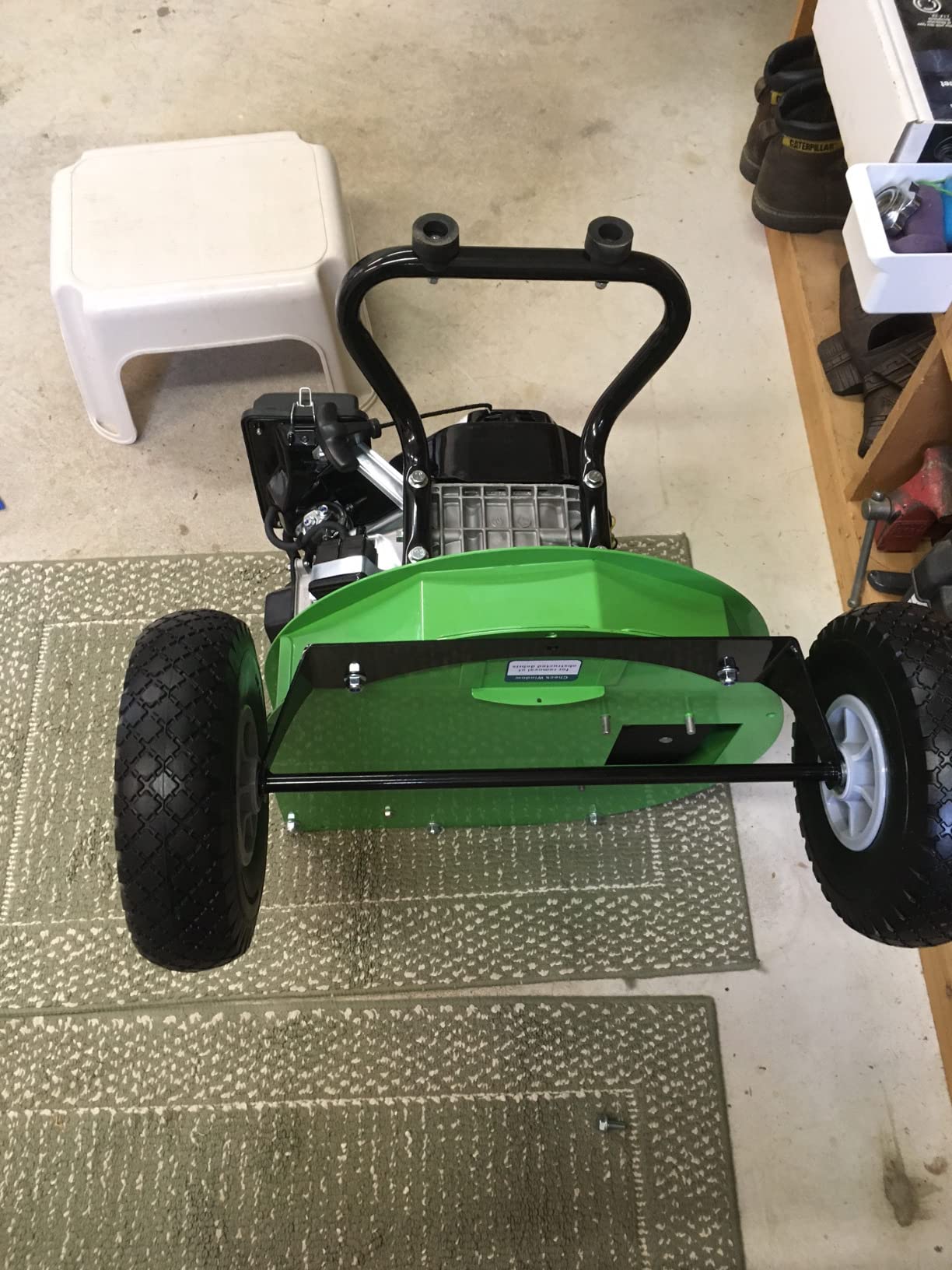 Owner assembling a GardenBeaut chipper upside down on a garage floor to bolt on the wheels