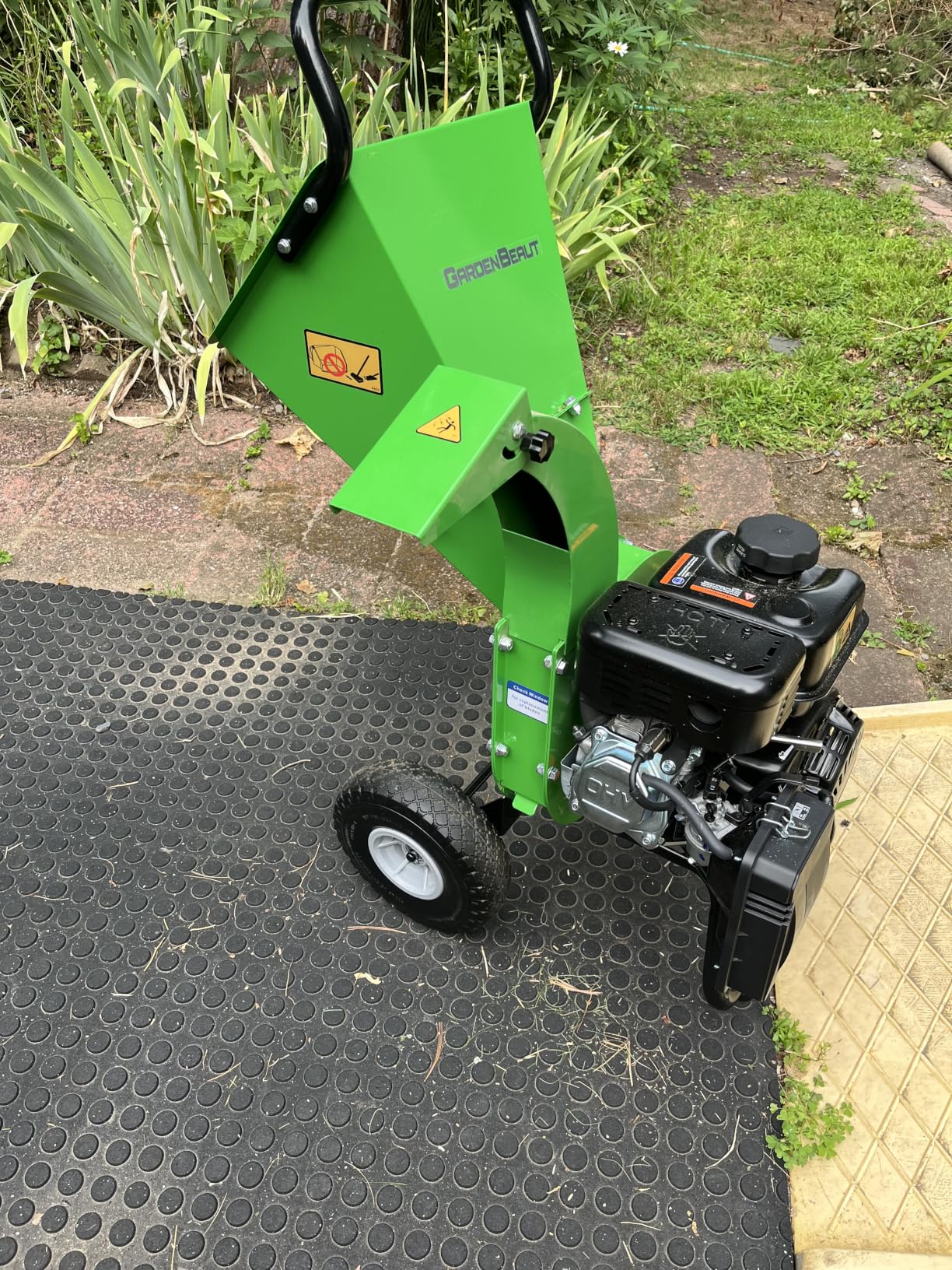 GardenBeaut wood chipper set up on a rubber mat beside a garden bed