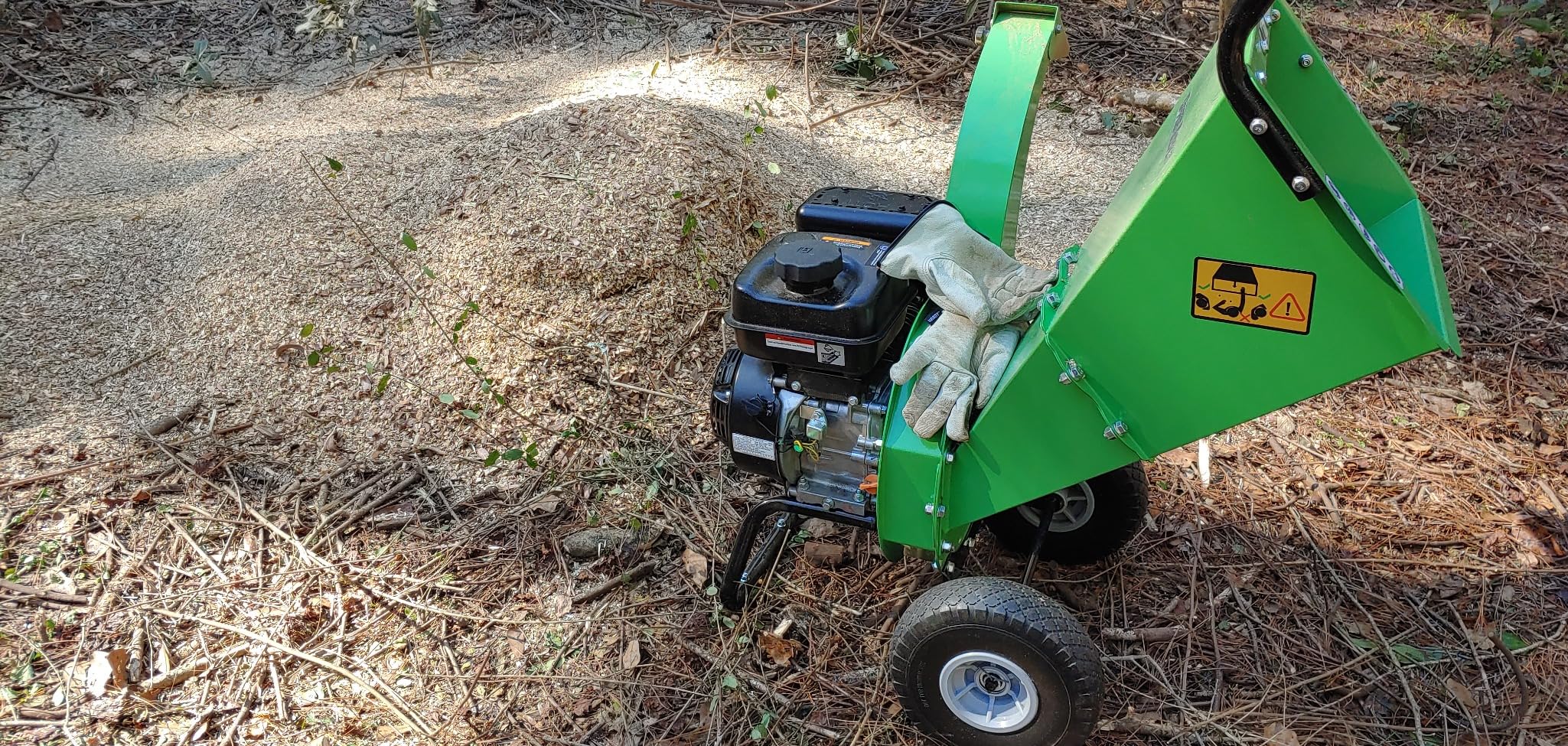 Work gloves resting on a GardenBeaut chipper beside a mound of fresh wood chips